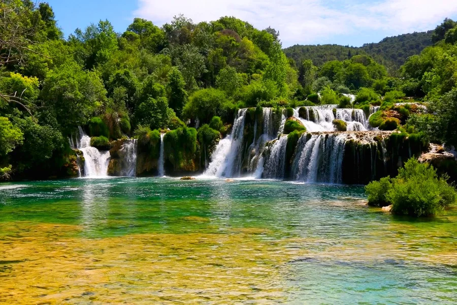 A wide waterfall spilling across the Krka river