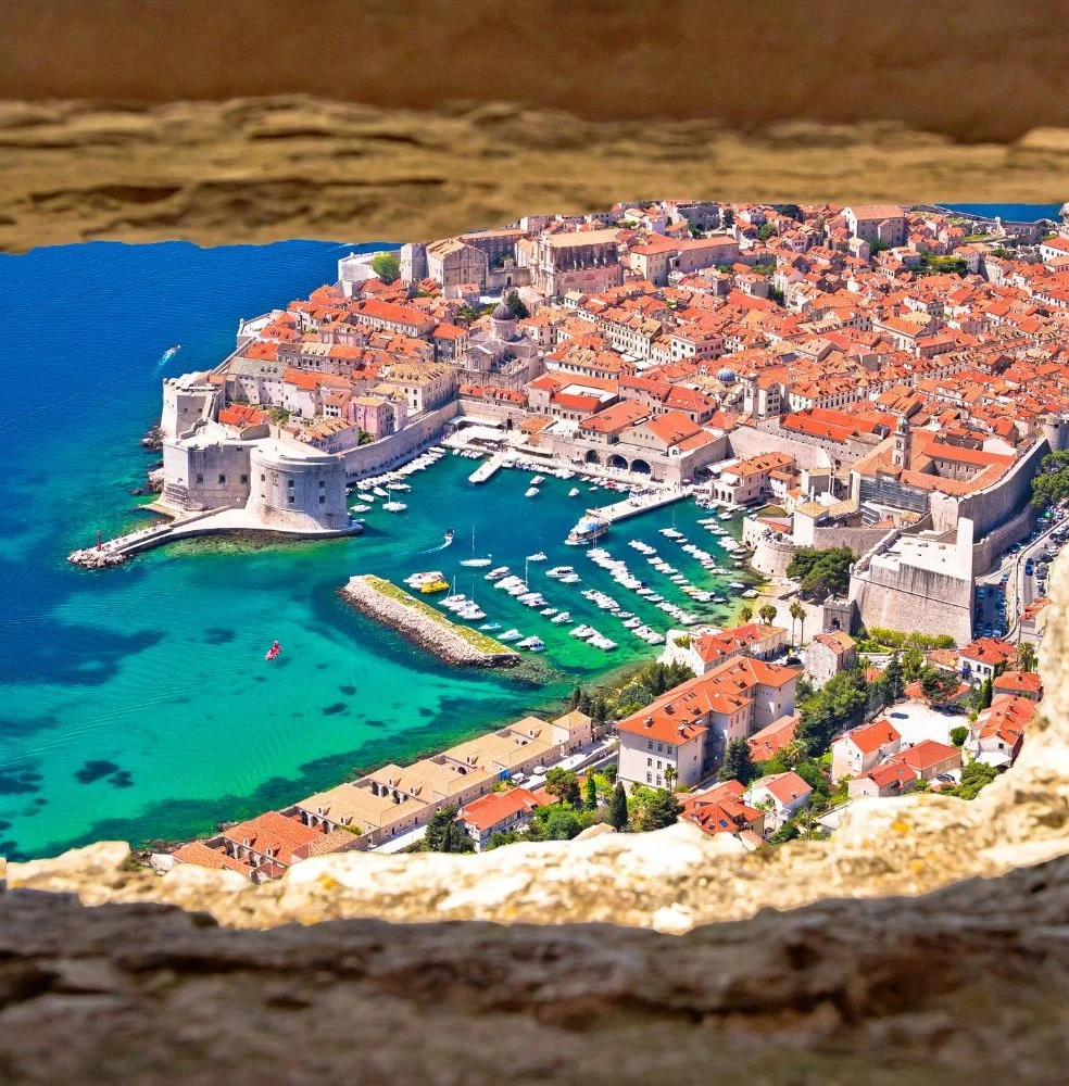 Dubrovnik old town and harbour, framed through a stone fortress window