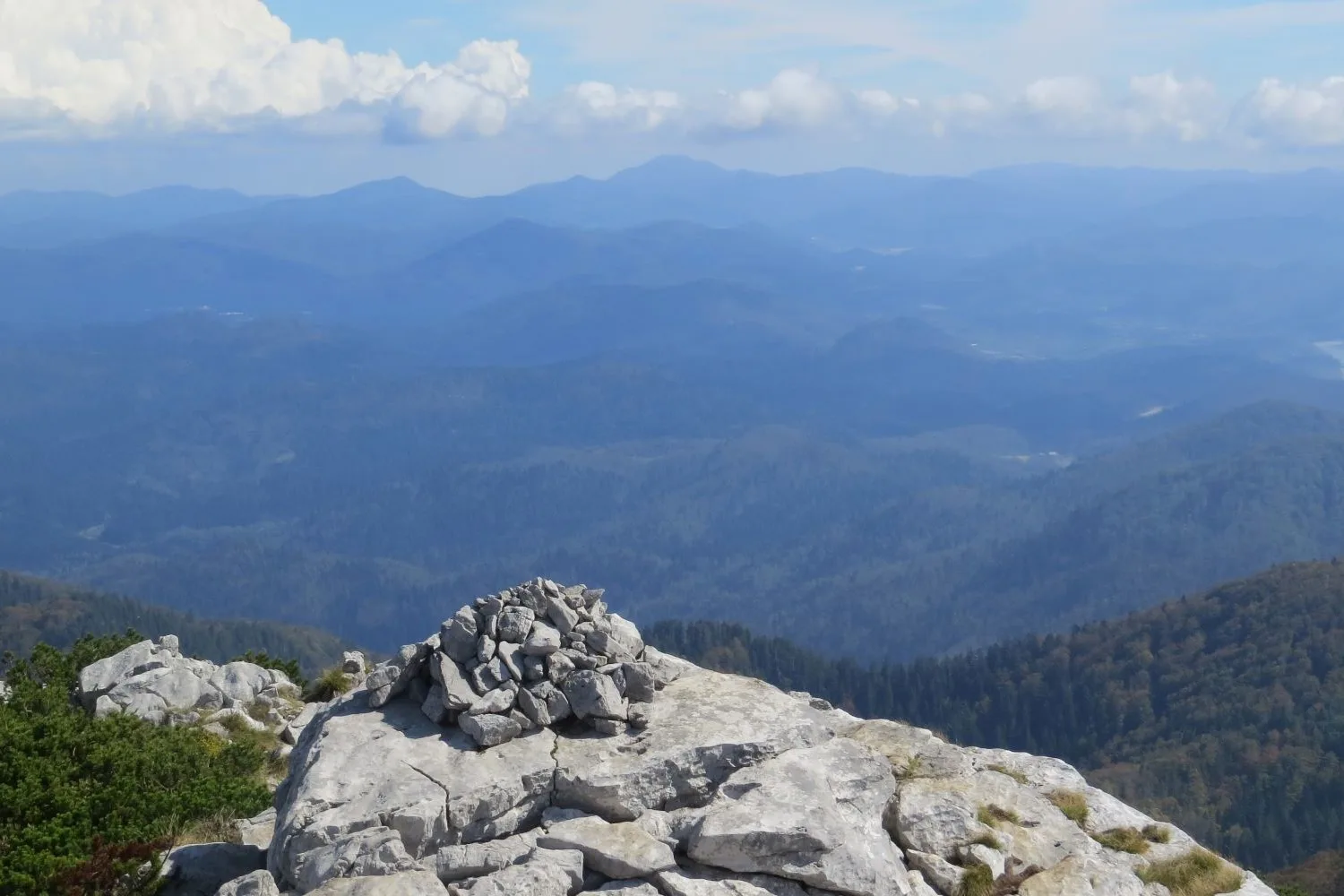 Summit cairn on Veliki Risnjak, with forested valleys below